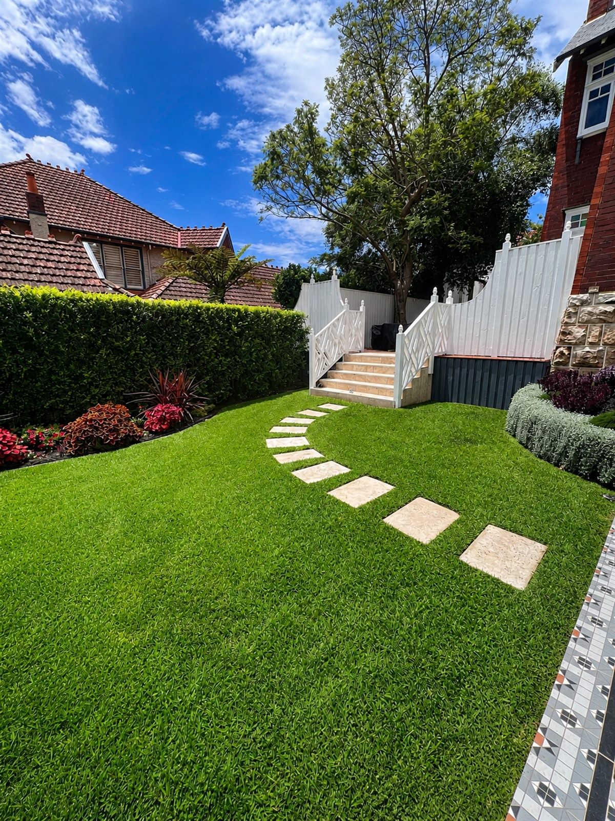 Residential garden with green lawn, stepping stones, and softscape planting by Eco Vision